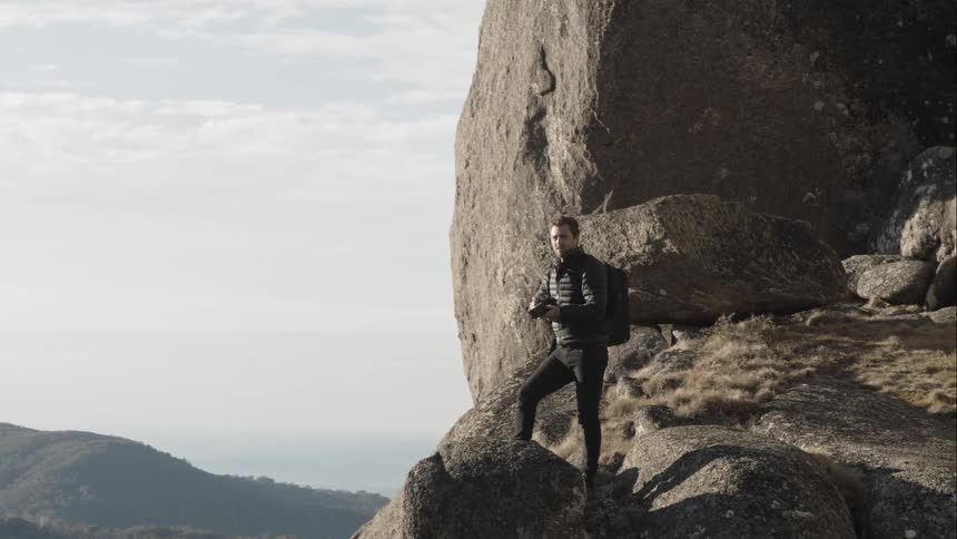 A man standing on a cliff taking photos