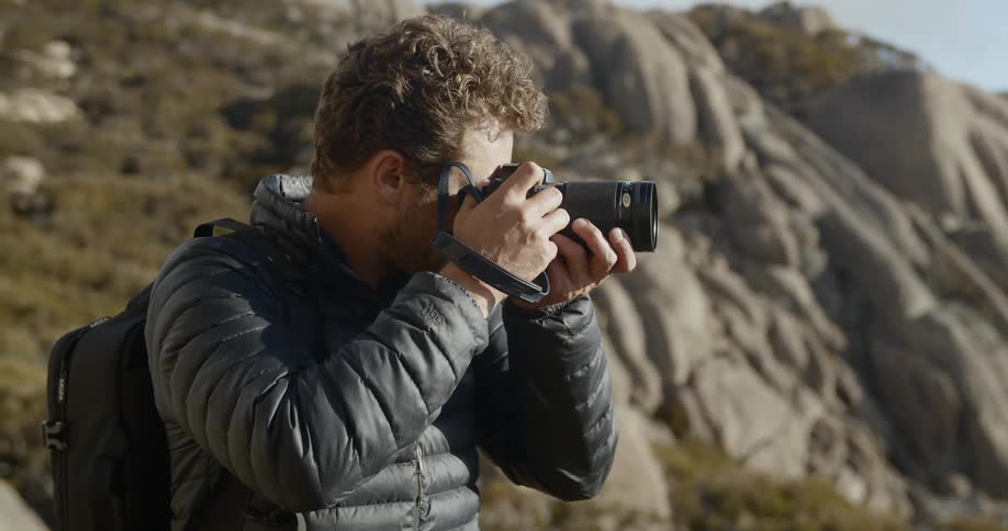 A man stands in a rocky area and takes pictures