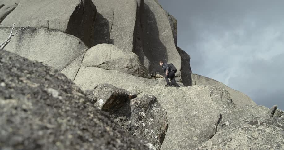 Man hikes across rocky mountain slope
