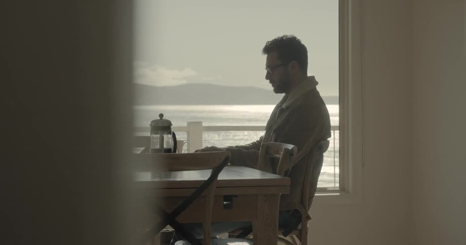 A caucasian male sitting at a table moving his hands