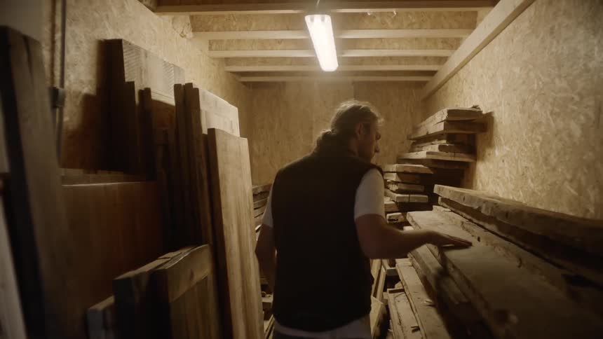 A man walking into a storage room full of wood