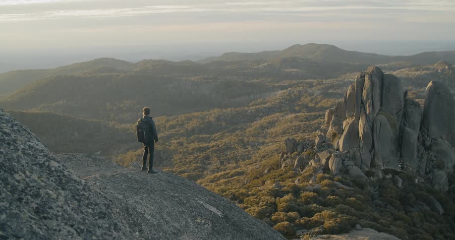 A white caucasian male standing on a gravel hill in the mountains