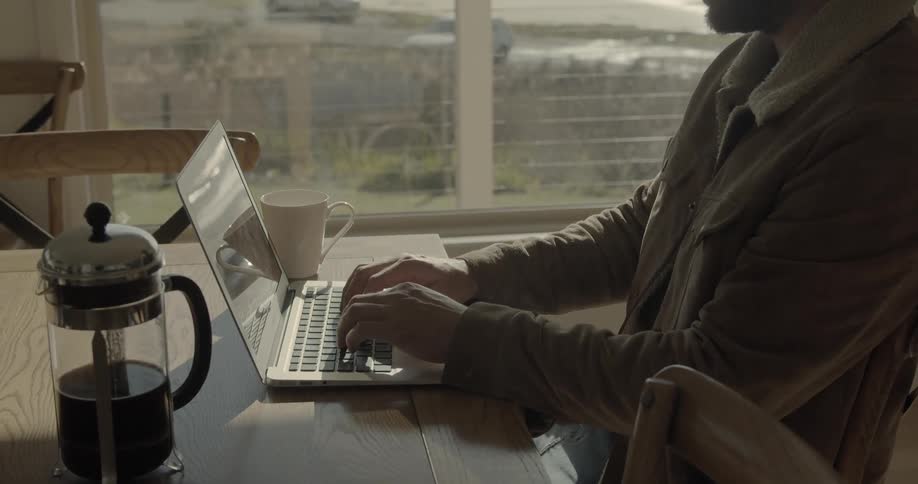 A man sitting at a table typing on a laptop