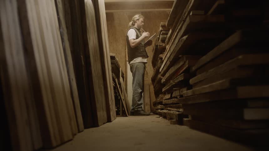 A man taking stock off wooden planks in a storehouse
