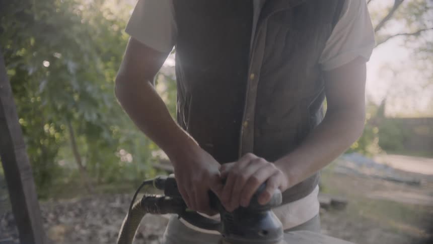A man sanding a wooden surface with a power sander