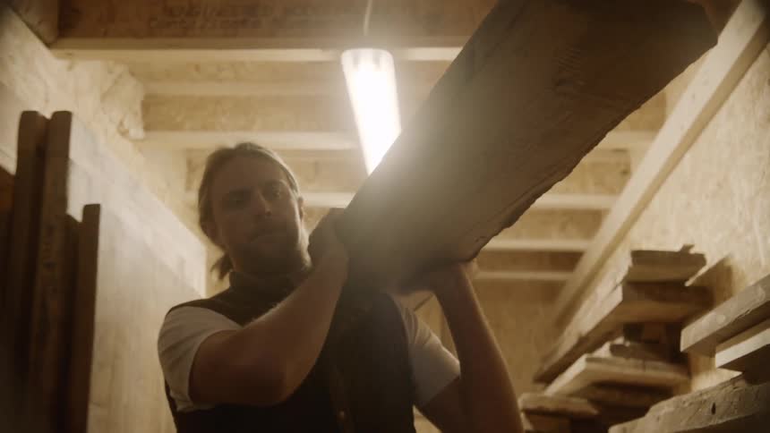 A man lifting a piece of wood over his shoulder
