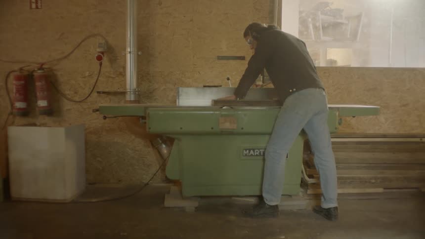 A young man cuts wood with a large machine