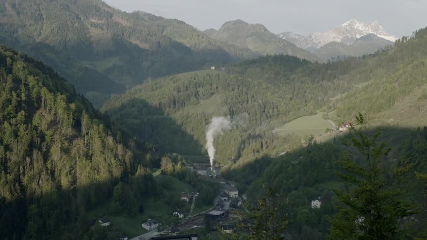 A town next to mountains with smoke coming out of a chimney