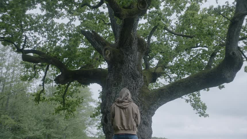 A female caucasian standing in front of a large tree