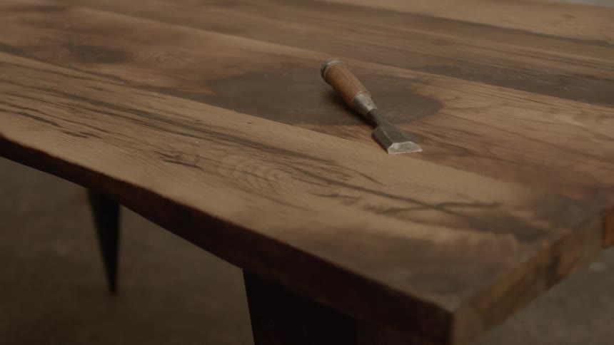 A wood carving knife sitting on a wooden plank table