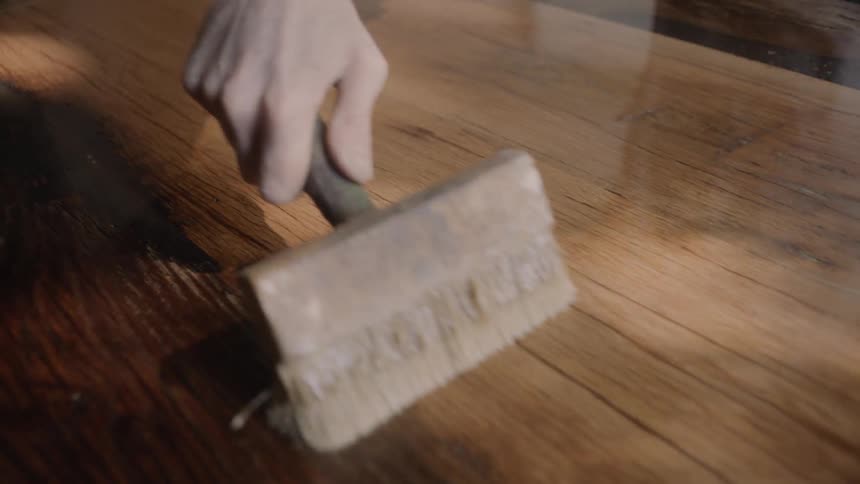A person using a brush to remove wood stain from wood