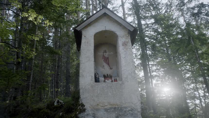 A cement structure with a painting of jesus holds little figurines