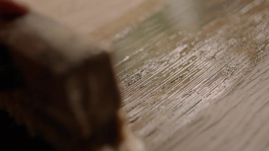 A person painting varnish on wood with a paintbrush