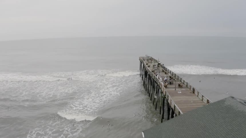 People stand on a pier looking out at the water