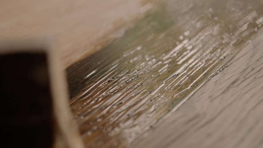 Brush spreads stain along grain of wood