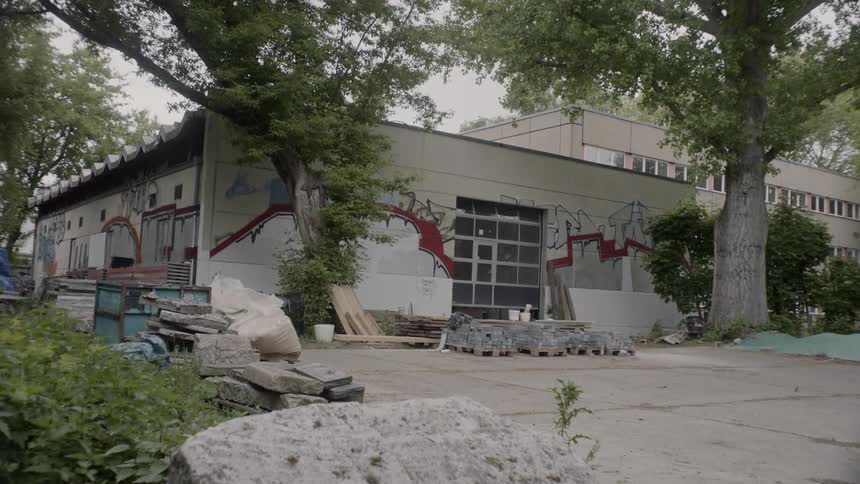 A glass garage door on the side of a concrete brick building raising during the day