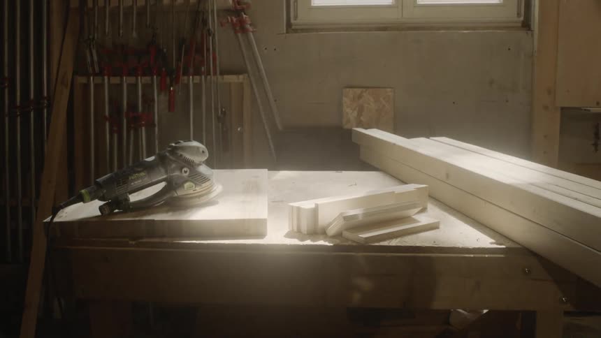 An electric sander sits on top of a wood project