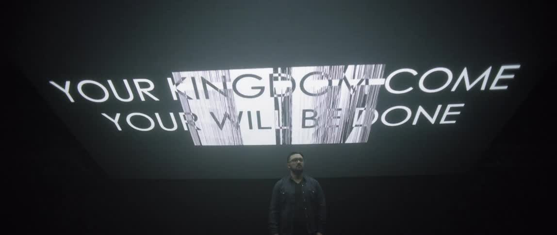 Words of scripture are projected behind and above a man