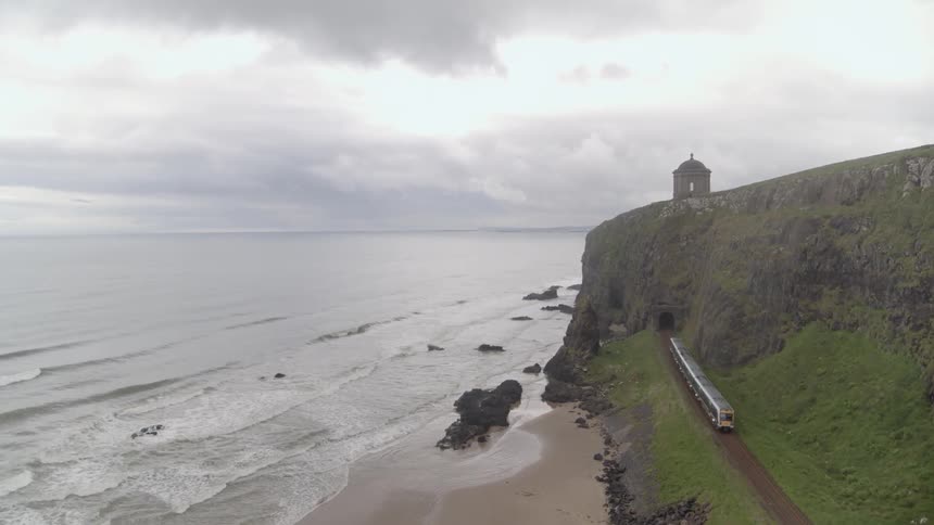 A train moves down the track to a tunnel along the coast