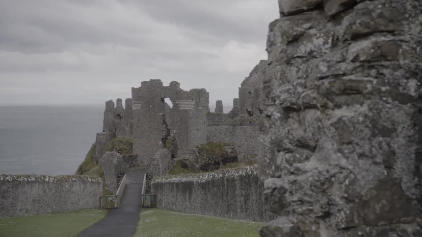 The ruined walls of dunluce castle on the coast under a cloudy sky