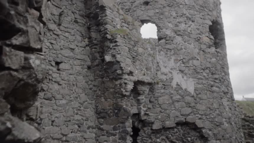 The partially standing stone walls of the ancient dunluce castle on a cloudy day