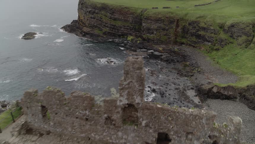 A ruined structure on a a headland above the sea during the day