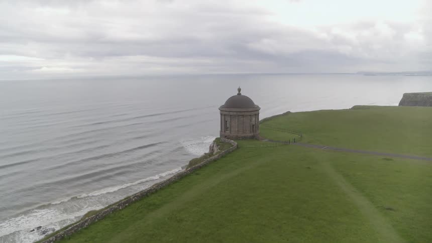A rotunda on a green field by the coast