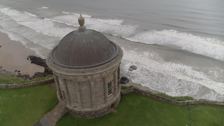 A domed building sits above the ocean