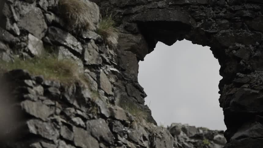 An archway in the partially standing stone walls of dunluce castle on a cloudy day