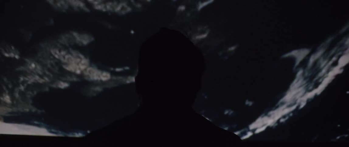A man looks up at the rocks above him