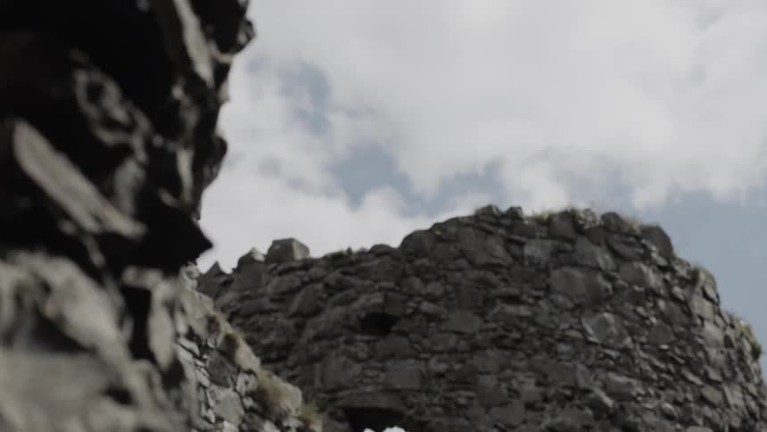The partially standing stone walls of an ancient castle under a cloudy sky