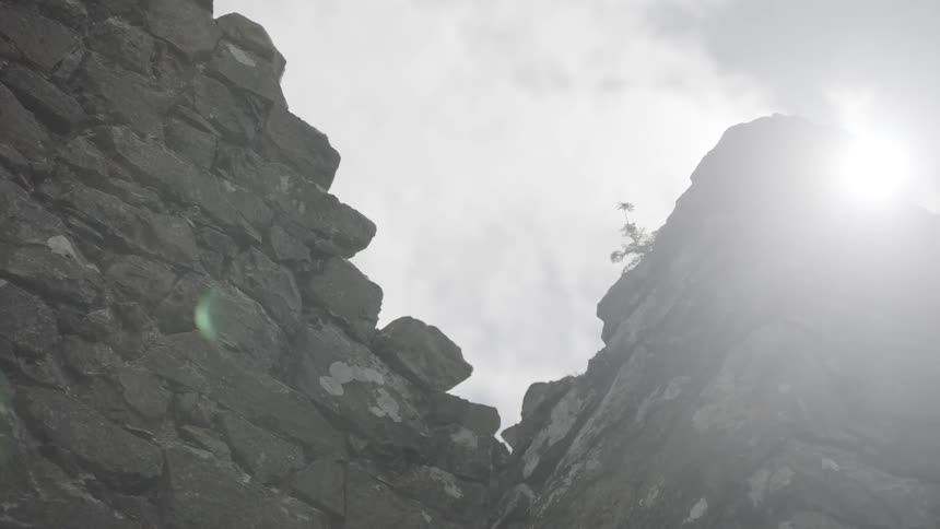 A cliff with the sky and the sun in the background