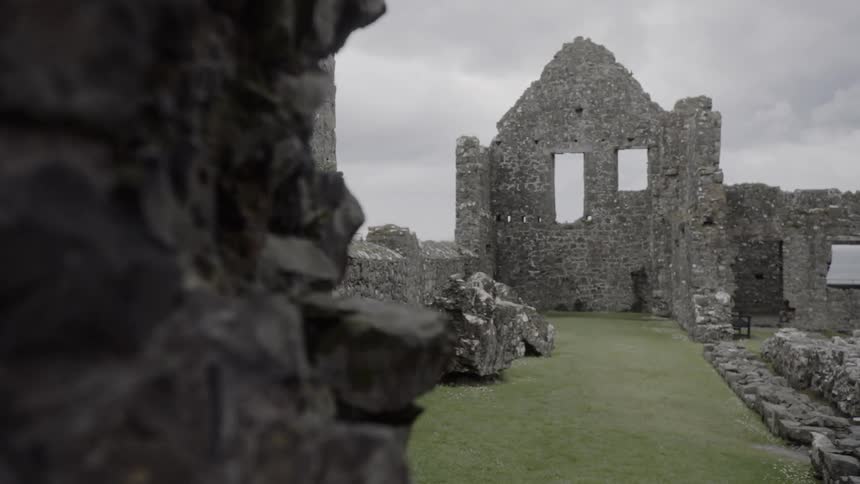The partially standing stone walls of the ancient dunluce castle on a cloudy day
