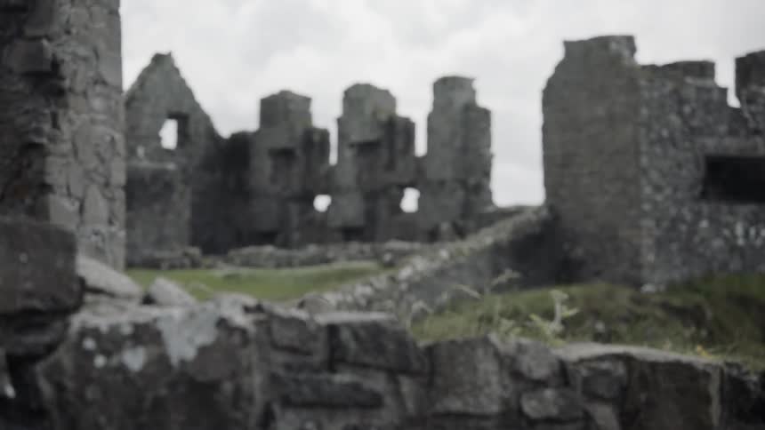 The partially standing stone walls of the ancient dunluce castle on a cloudy day