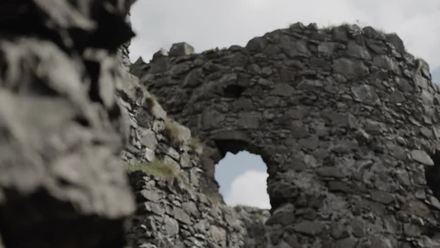 A cloud is visible through a hole in a rock wall