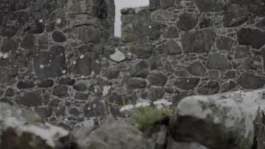 A window in the partially standing stone walls of the ancient dunluce castle on a cloudy day