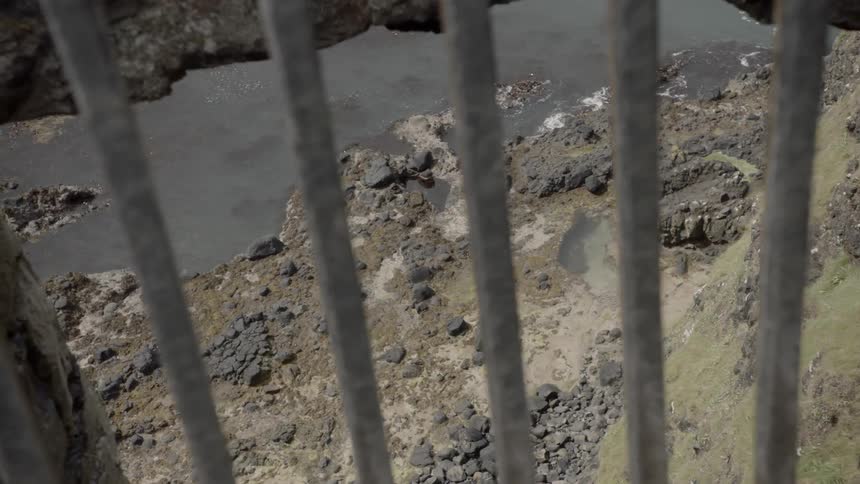 A rocky coastline seen through bars from above