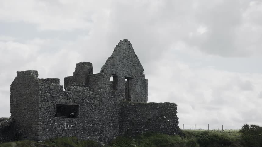 The partially standing stone walls of a large ancient monument on the coast