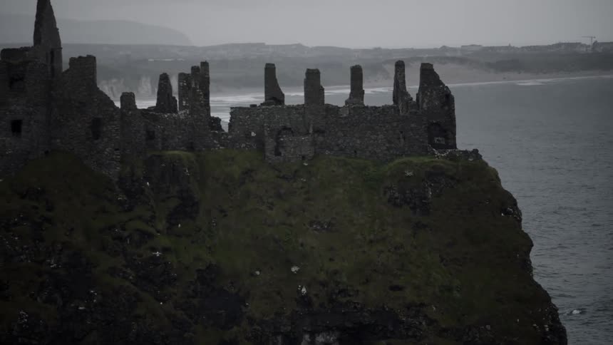 The partially standing stone walls of the ancient dunluce castle on a cloudy day