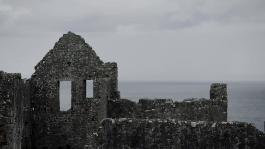 Ruined keep borders the sea under a cloudy sky