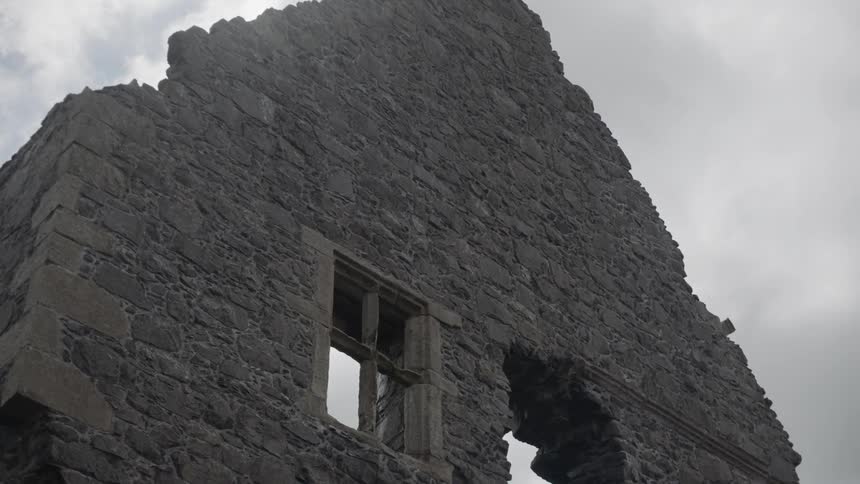 The partially standing stone walls of a large ancient monument on the coast