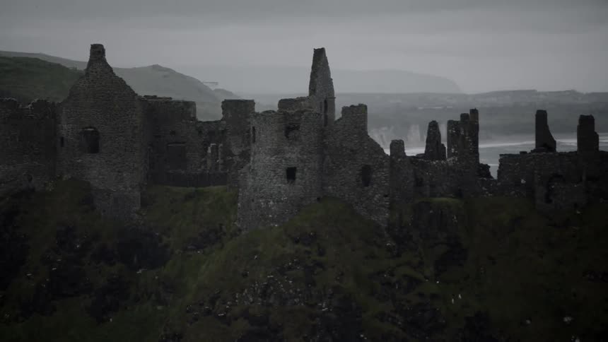 The partially standing stone walls of dunluce castle on a cloudy day