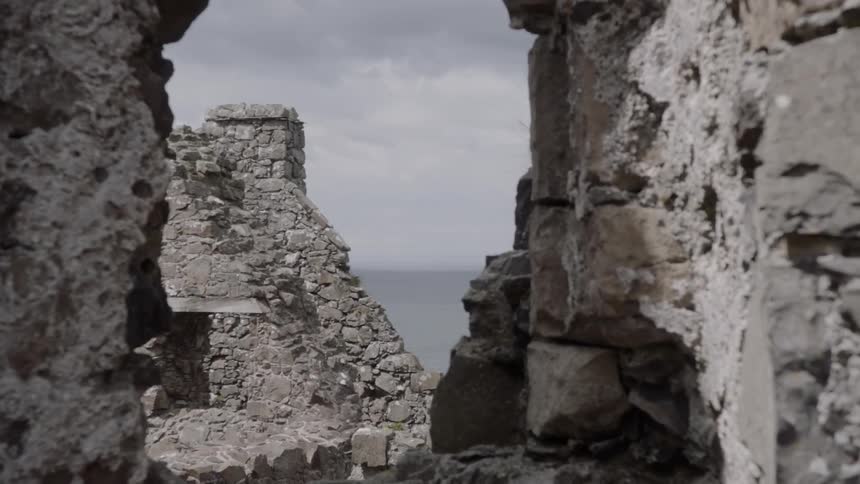 The partially standing stone walls of a large historical site on the coast