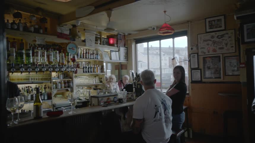 A crowd of white people inhabit a small bar