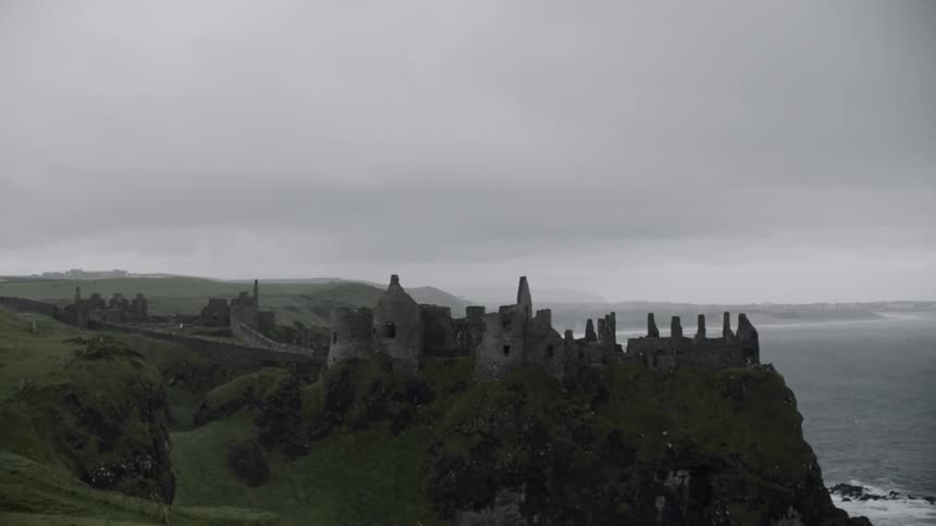 The partially standing stone walls of a large ancient castle on the coast