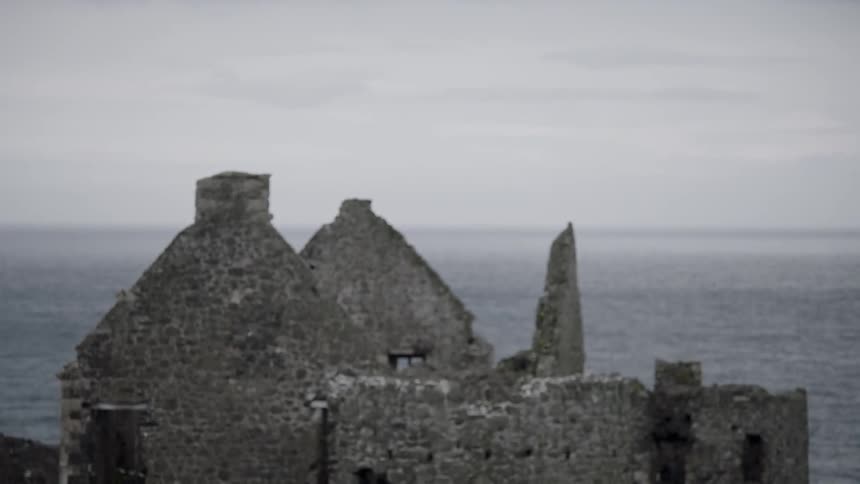 The stone walls of dunluce castle under a cloudy sky