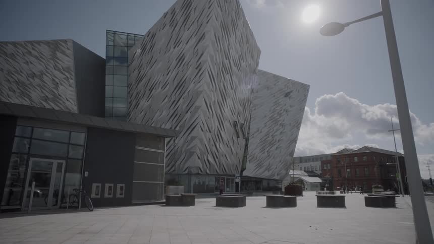 A man walks in front of a building with a modern architectural design