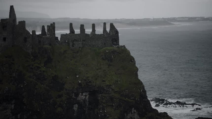 The partially standing stone walls of dunluce castle on a cloudy day
