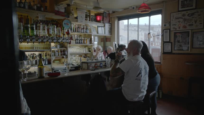 People sit in small pub during the day smiling