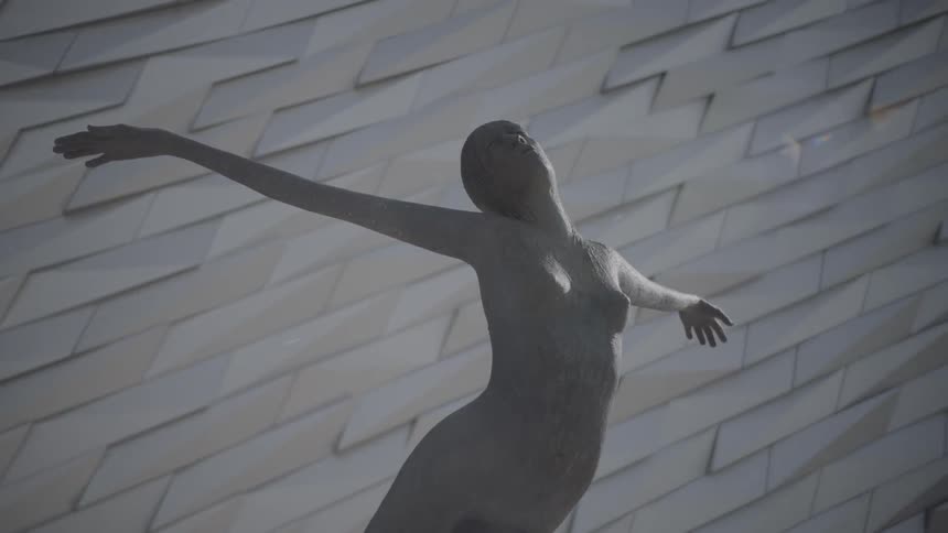 A statue of a woman with her arms out and the sky in the background